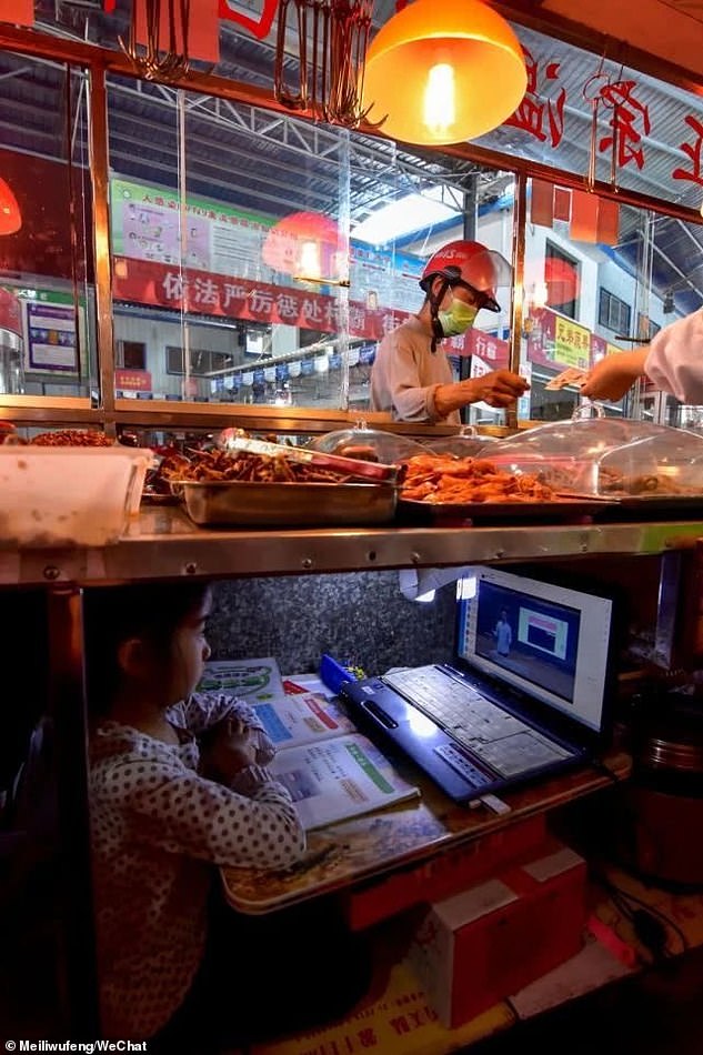 Chinese girl studying under her parents' food stall table